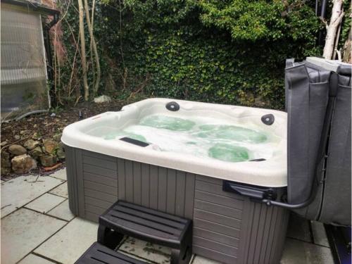 a large bath tub with green water in it at Pass the Keys A unique and cosy cottage - optional hot tub in Church Stretton
