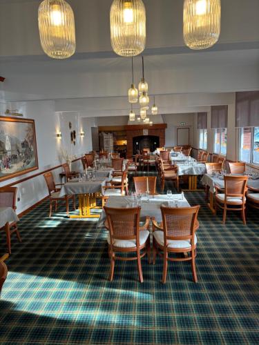 een eetkamer met tafels en stoelen en kroonluchters bij Hotel & Restaurant Le Cardinal in Poix