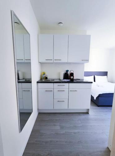 una cocina con armarios blancos y una cama en una habitación en Urban Oasis with Queen Bed and View BE-38, en Zúrich