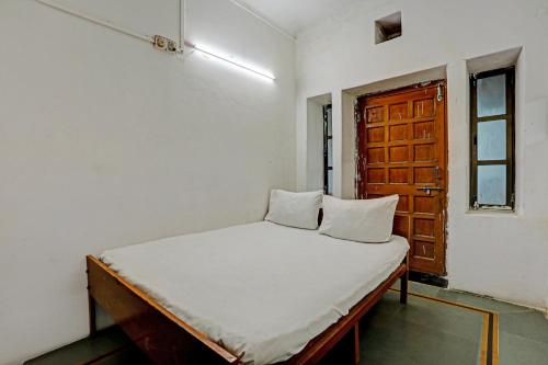 a bed in a room with a wooden door at OYO Hotel Neelkamal palace and Guest house in Nāthdwāra