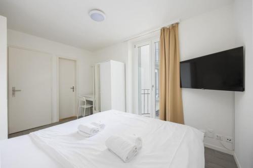 a bedroom with a white bed with a flat screen tv at Urban Oasis with Queen Bed and View BE-19 in Zürich