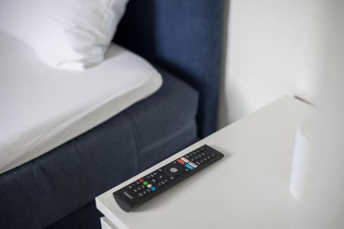 a remote control sitting on a table next to a bed at Urban Oasis with Queen Bed and View BE-19 in Zürich