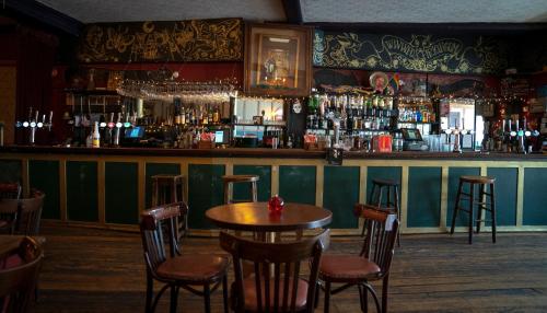 a bar with a wooden table and some chairs at Firkinn in London