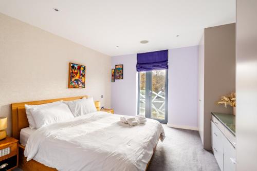 a bedroom with a large white bed and a window at King beds apartment with en-suite, private balcony and elevator by iconic Portobello Market in London