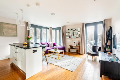 a kitchen and living room with a purple couch at King beds apartment with en-suite, private balcony and elevator by iconic Portobello Market in London