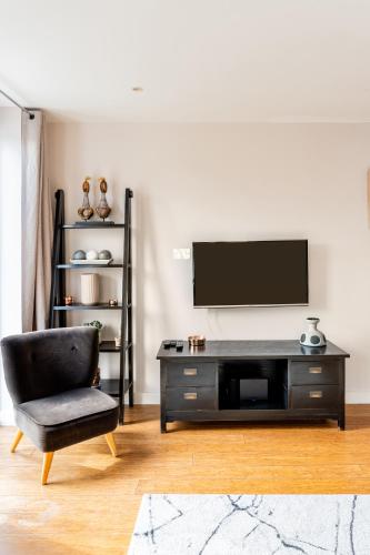 a living room with a tv and a chair at King beds apartment with en-suite, private balcony and elevator by iconic Portobello Market in London