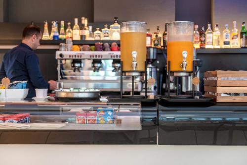 a man standing behind a bar with two pitchers of beer at Domino Suite Hotel & Residence in Lido di Jesolo