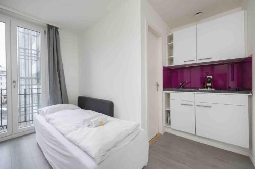 a white room with a kitchen with purple cabinets at Cozy Urban Studio in the City BE-21 in Zurich
