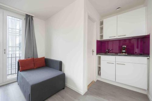 a room with a couch and a kitchen with purple cabinets at Cozy Urban Studio in the City BE-21 in Zurich