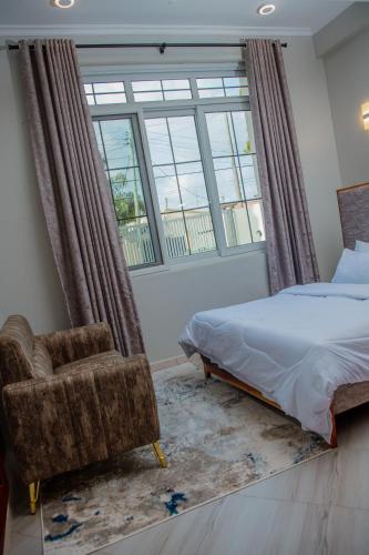 sypialnia z łóżkiem, krzesłem i oknem w obiekcie Mine Apartment w mieście Dar es Salaam