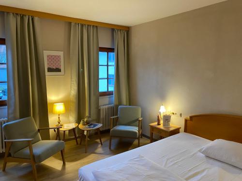 a hotel room with a bed and chairs and a window at Hotel-Restaurant & Metzgerei Rößle in Dettingen an der Erms