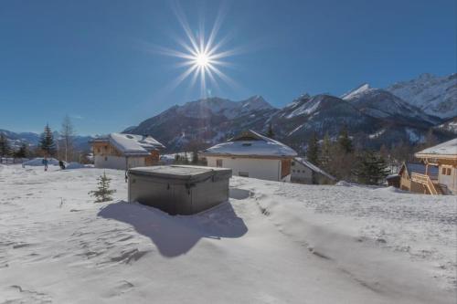 un soleil brille au-dessus d'un village enneigé avec des bâtiments dans l'établissement Luxury resort 5* Serrechevalier, au Monêtier-les-Bains