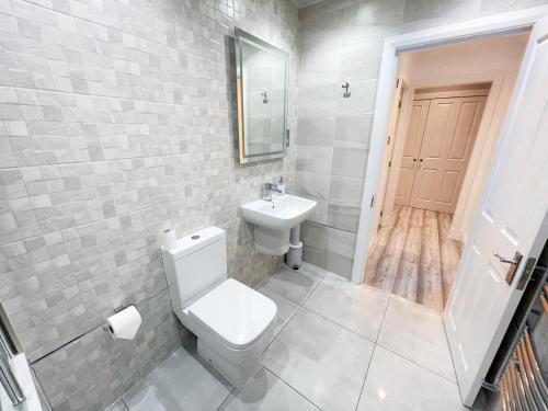 a bathroom with a white toilet and a sink at Recently Refurbished Two Bedroom Apartment, Central Location! in Glasgow