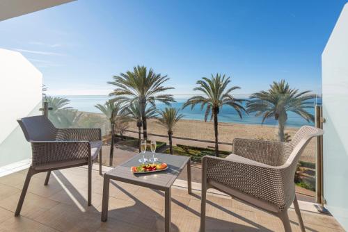 two chairs and a table on a balcony with palm trees at HSM Golden Playa in Playa de Palma