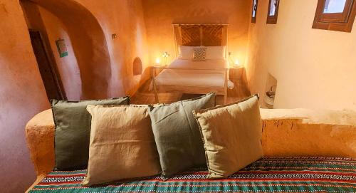 um quarto com uma cama e algumas almofadas em Bait Al Aali Guesthouse em Al Hamra