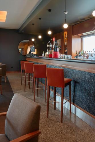 a bar with red chairs and a counter at Hotel Versatile in Guarda