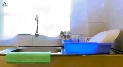 a kitchen counter with a sink with a container of dishes at Arctic Tern airbnb Mwea 