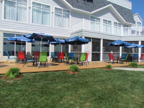 a group of chairs and umbrellas in front of a building at Lakeside Resort & Conference Center in Houghton Lake