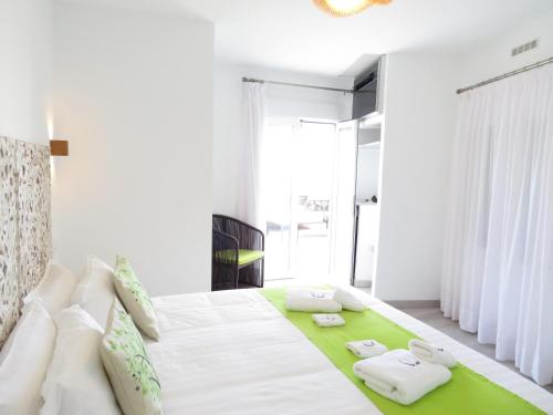a white bedroom with a large bed with a green rug at Lua Hotel Boutique in El Pinar del Hierro
