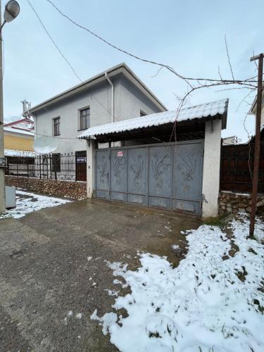 una casa con un garaje con nieve en el suelo en Мини-гостиница АЙ, en Shymkent