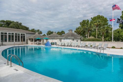a large blue swimming pool with chairs and a building at Sea Palms Resort St Simons Island in Saint Simons Island