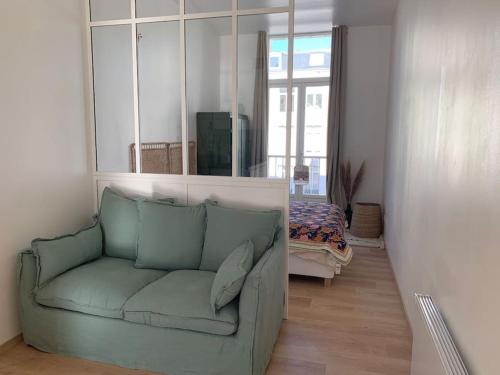 a living room with a green couch and a mirror at Appartement centre ville avec terrasse in Lille