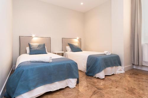 two beds with blue and white sheets in a room at VTZ The Orus Factory Hotel - Parking Muy Económico in Zaragoza