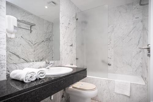 a white bathroom with a sink and a toilet at VTZ The Orus Factory Hotel - Parking Muy Económico in Zaragoza