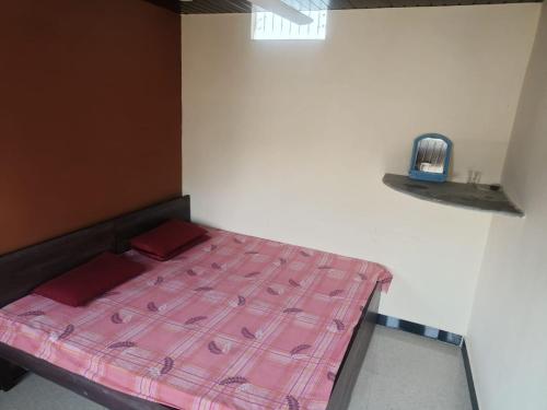 Kailash kuti Guest House في اوجاين: سرير في غرفة مع بطانية وردية عليه