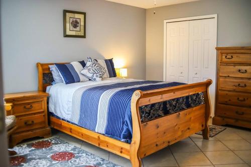 a bedroom with a wooden bed with blue and white sheets at NEW Sunny Escape! Enjoy TV by your Private Pool Mins from Disney in Davenport