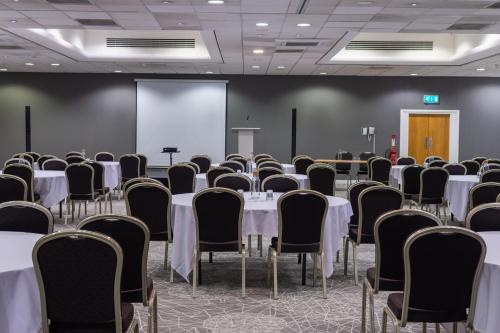 a conference room with tables and chairs and a screen at Holiday Inn Liverpool City Centre by IHG in Liverpool
