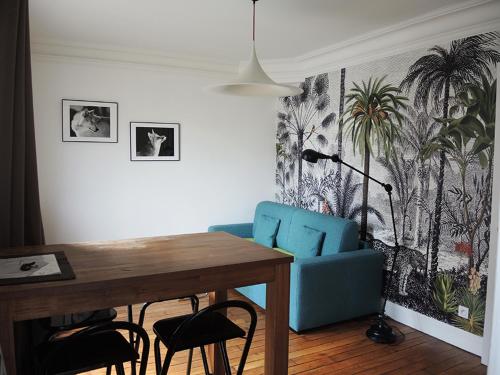 ein Esszimmer mit einem blauen Stuhl und einem Tisch in der Unterkunft 2 Pièces avec Balcon Plein Sud in Paris