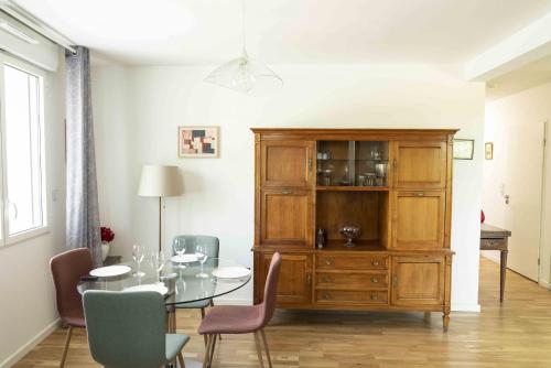 d'une salle à manger avec une table et une armoire en bois. dans l'établissement Queyries -2 chambres Parking Ascenseur Balcon Rive Droite, à Bordeaux