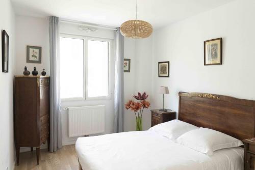 1 dormitorio con cama blanca y ventana en Queyries - Appartement 2 chambres avec Parking, en Burdeos