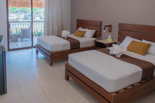 a hotel room with two beds and a balcony at Xuux Peek by Tecnohotel in Yaxché