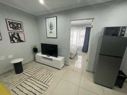 Trendy, Comfortable 1 bedroom Apartments in Mthatha في امتاتا: غرفة معيشة مع تلفزيون بشاشة مسطحة على جدار