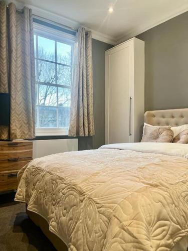 um quarto com uma cama grande e uma janela em Flat in the heart of Holland Park em Londres