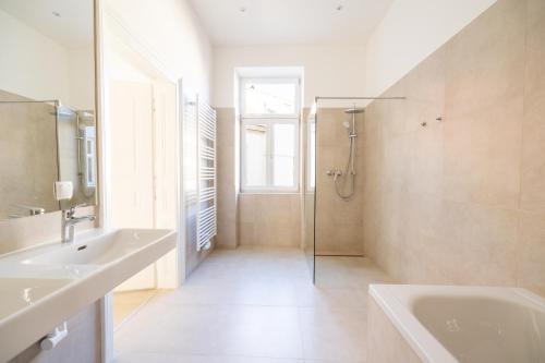 ein Bad mit einer Badewanne, einem Waschbecken und einer Dusche in der Unterkunft Rochus Stylish Stays in Wien