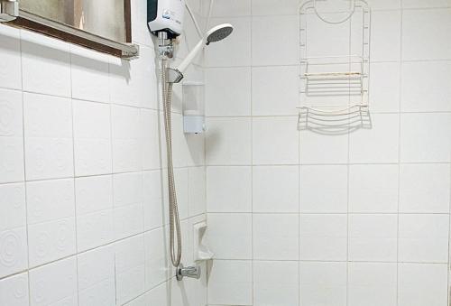 a shower in a white tiled bathroom at RedDoorz @ Tandikan Beach Cottages in El Nido