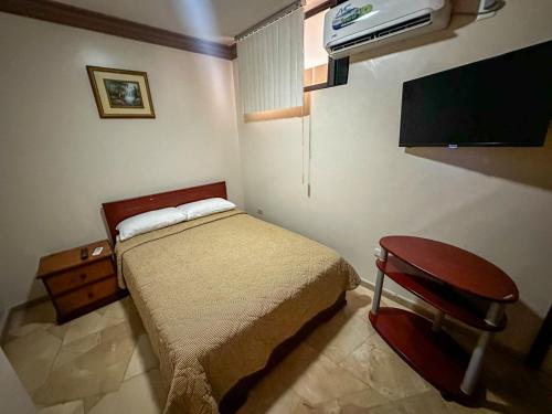 a small bedroom with a bed and a tv at Hotel Bucaneiro in Manta