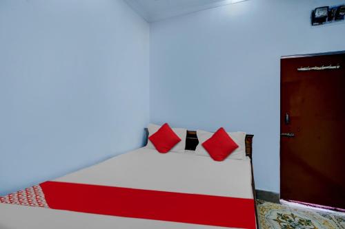 ein Schlafzimmer mit einem Bett mit roten Kissen in der Unterkunft Hotel Sourya Residency in Jamshedpur