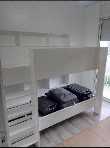 a white shelf with two bags of luggage on it at Appartement moyen standing in Inezgane