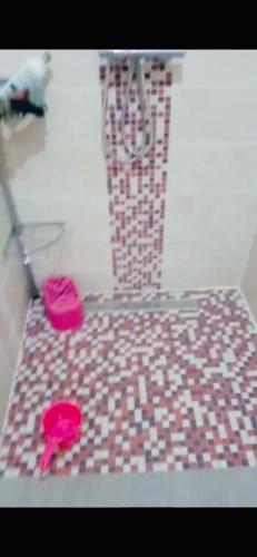 a bathroom with two pink slippers on a tile floor at Appartement moyen standing in Inezgane
