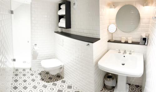a white bathroom with a sink and a toilet at Hotel Litteraire Marcel Ayme, BW Premier Collection in Paris