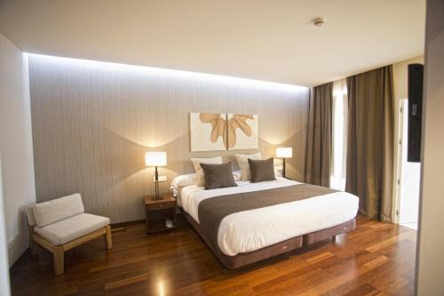 a bedroom with a large bed and a chair at Carris Cardenal Quevedo in Ourense