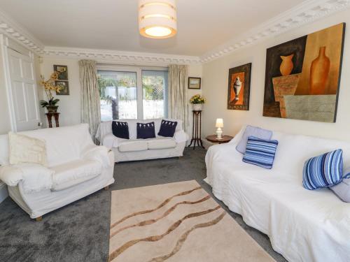 a living room with two white couches and a window at 11 Glyn Garth Mews in Llandegfan