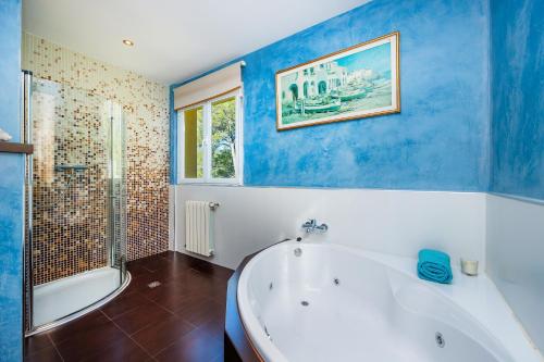 een blauwe en witte badkamer met een bad en een douche bij Villa Portals One in Portals Nous