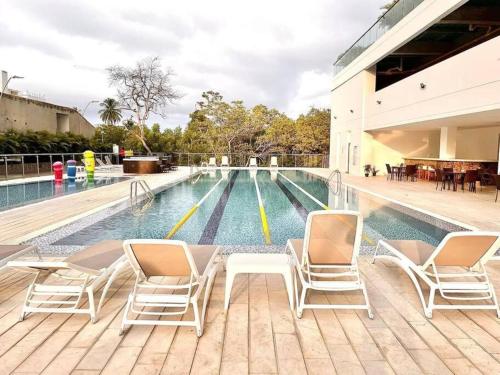 a swimming pool with chairs and a table next to a building at Increible apartamento Samaria Club de Playa, Santa Marta, Pozos colorados in Gaira