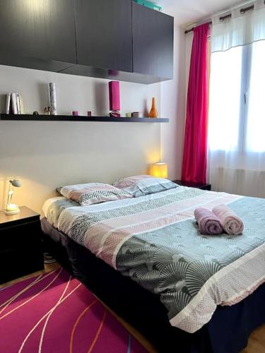 een slaapkamer met een bed met roze kussens erop bij Charmant appartement tout équipé avec 2 chambres in Ivry-sur-Seine