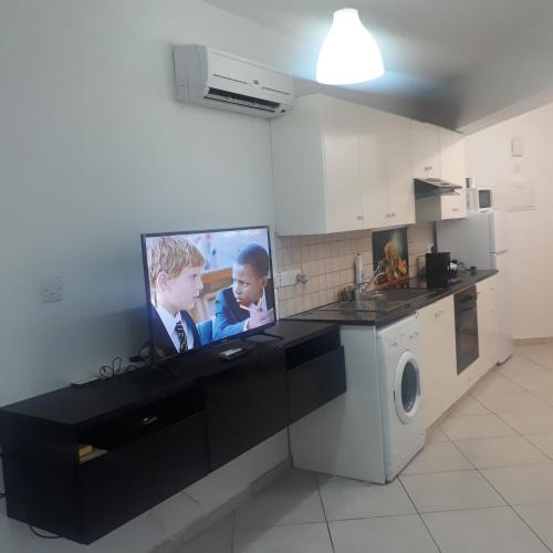 a kitchen with a flat screen tv on a counter at A CHEERFUL APARTMENT in a popular area in Pallouriotissa